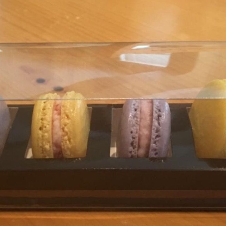 Close-up of three macarons inside black macaroon box showing insert spacing