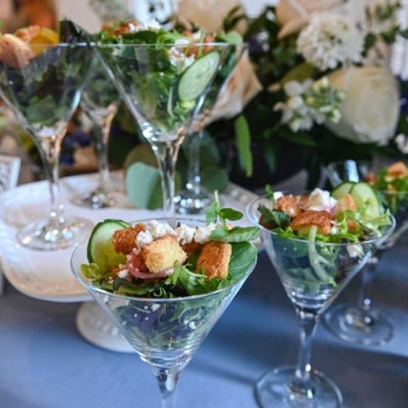 Acrylic martini-style cups filled with salads and appetizers at an event
