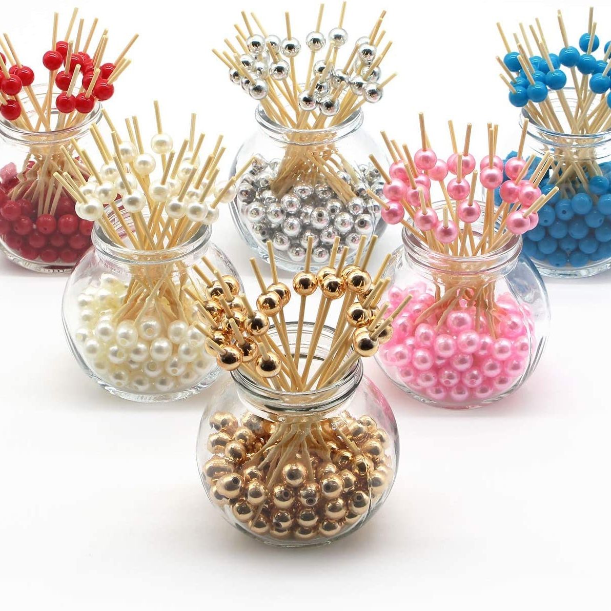 Assorted color fancy toothpicks displayed in glass jars featuring red, pearl, gold, silver, pink and blue decorative beads.