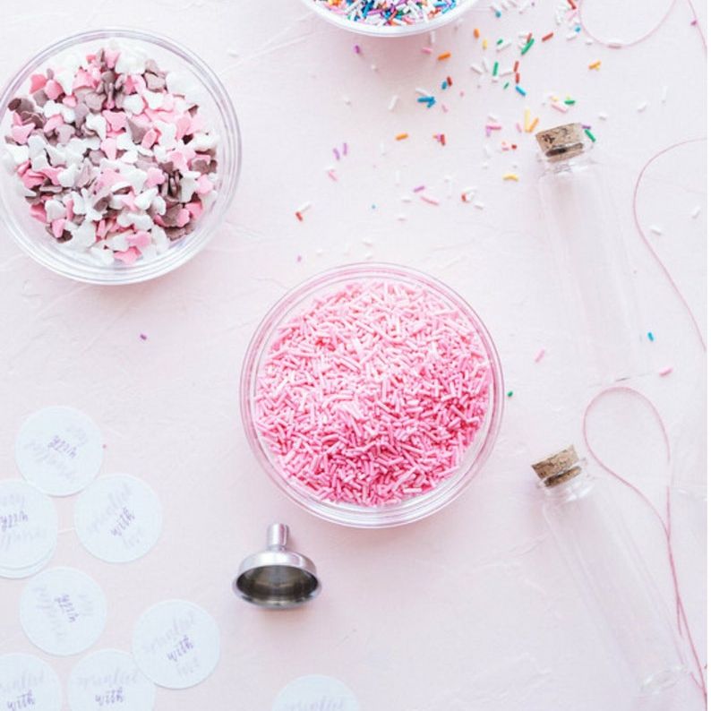 Baby shower sprinkle favors displayed on a dessert table.