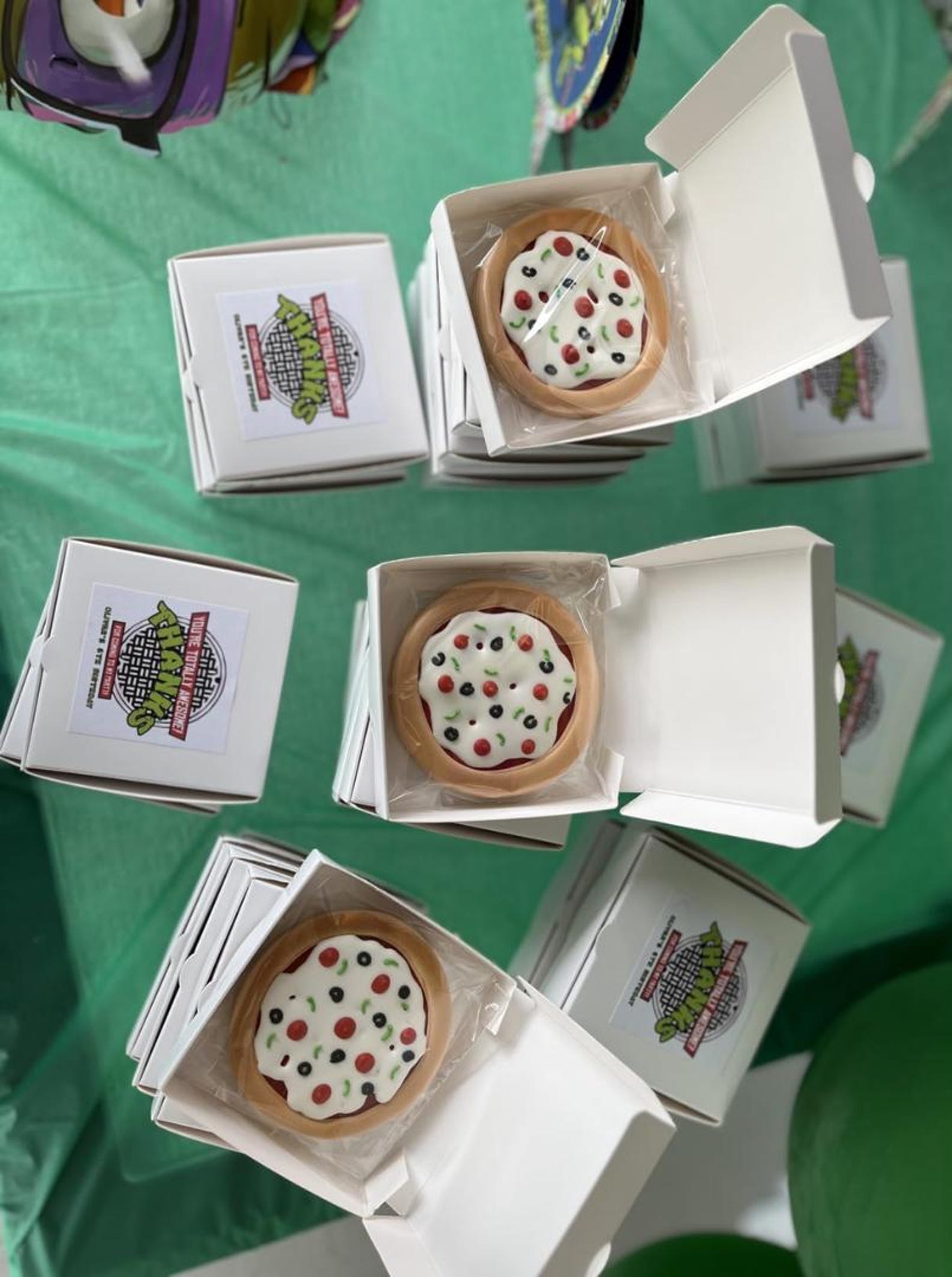 Mini pizza boxes filled with candies at a vibrant birthday party.