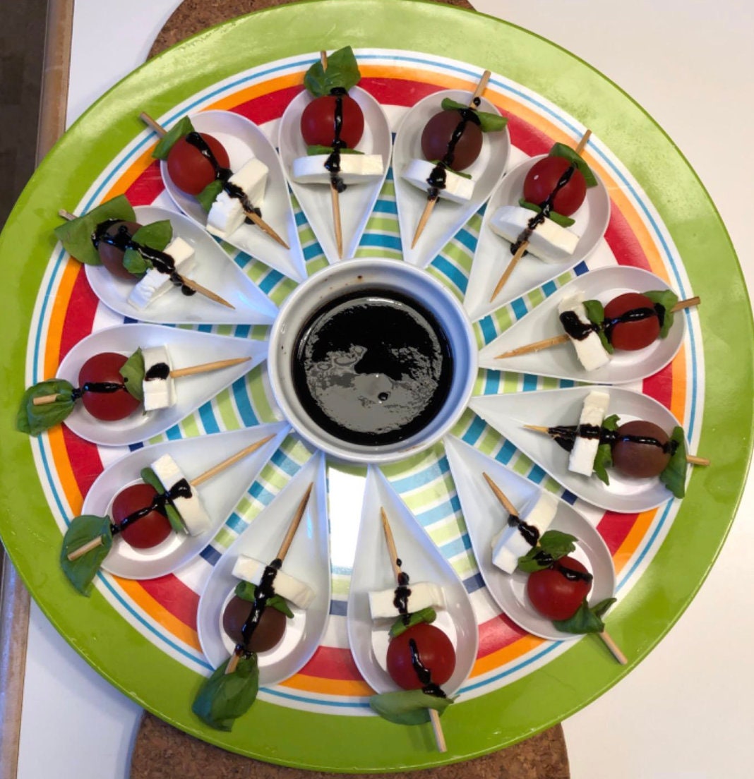 Black tasting spoon with caprese salad and fresh basil.