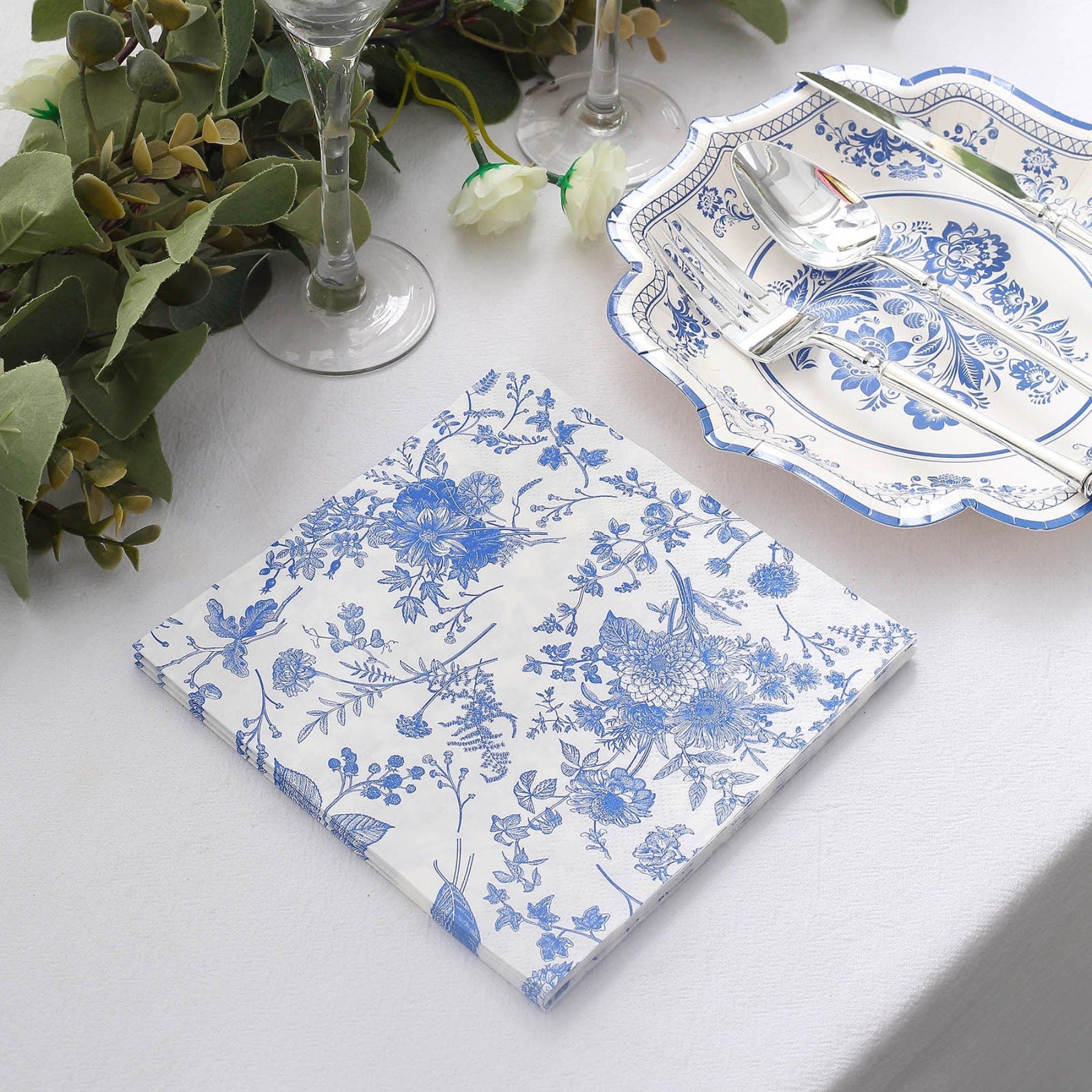 Blue chinoiserie napkin with floral print next to disposable scallop rim plates