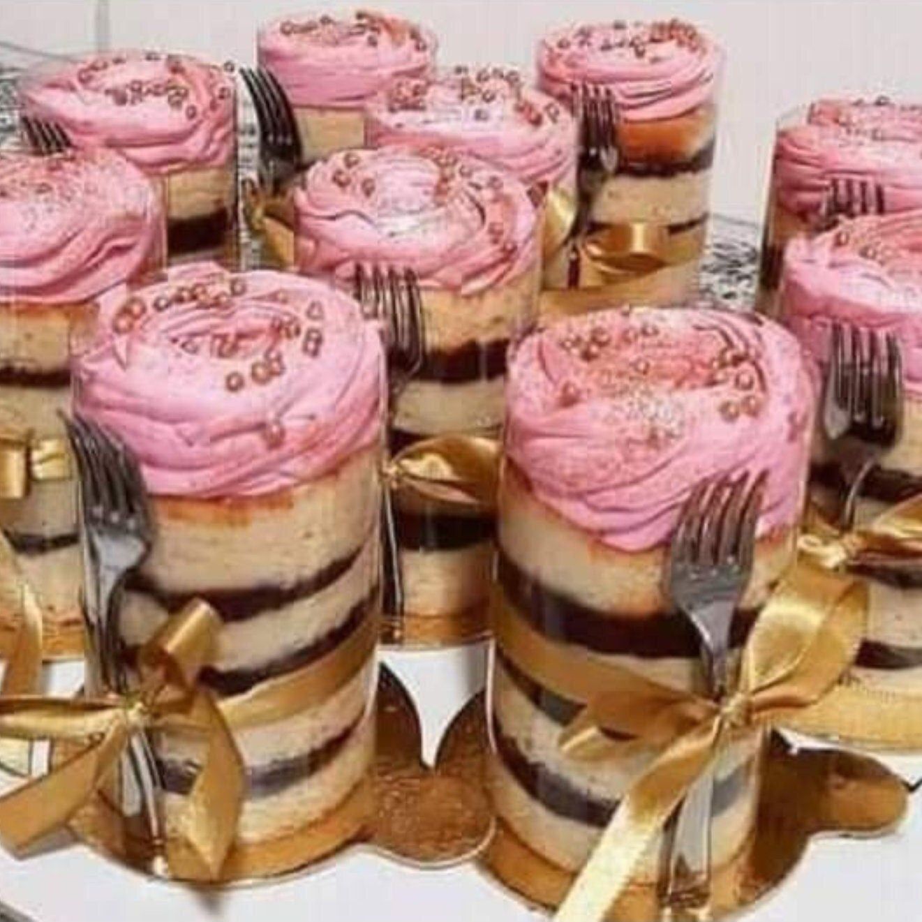 Wrapped cake displayed at a bridal shower dessert table, featuring a clear cake wrap on a gold board with a fork.