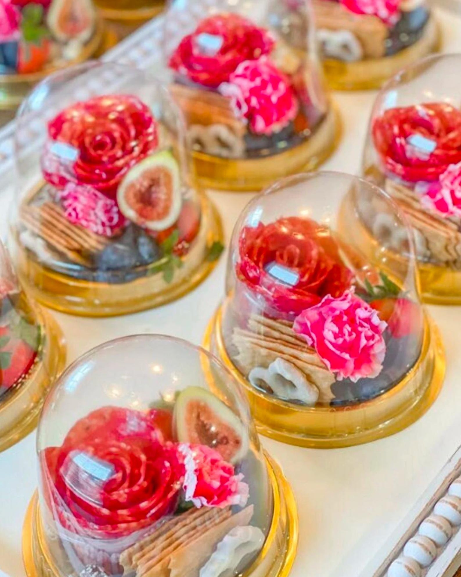 Clear charcuterie domes filled with layered desserts, gold toothpicks, and mini forks.