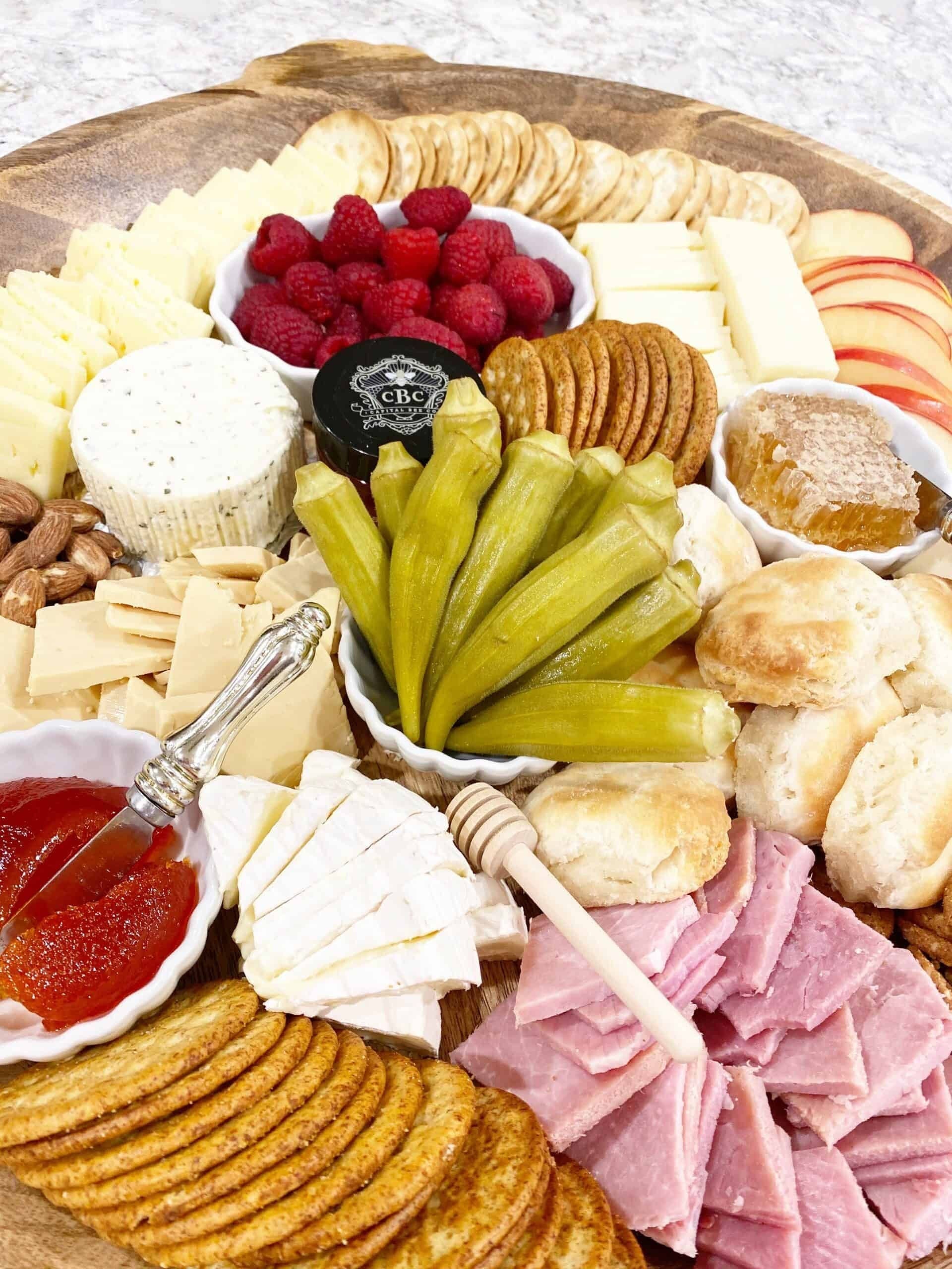 Cheese and charcuterie platter styled with wooden honey dipper and fruit