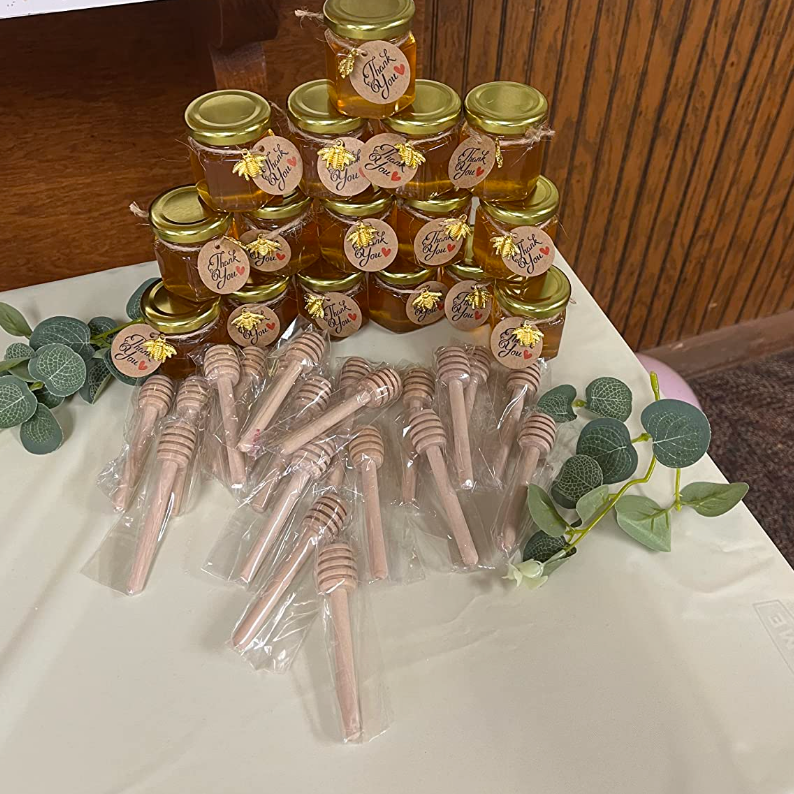 Gold-lidded mini honey jars wrapped with twine, styled on an elegant dessert table.
