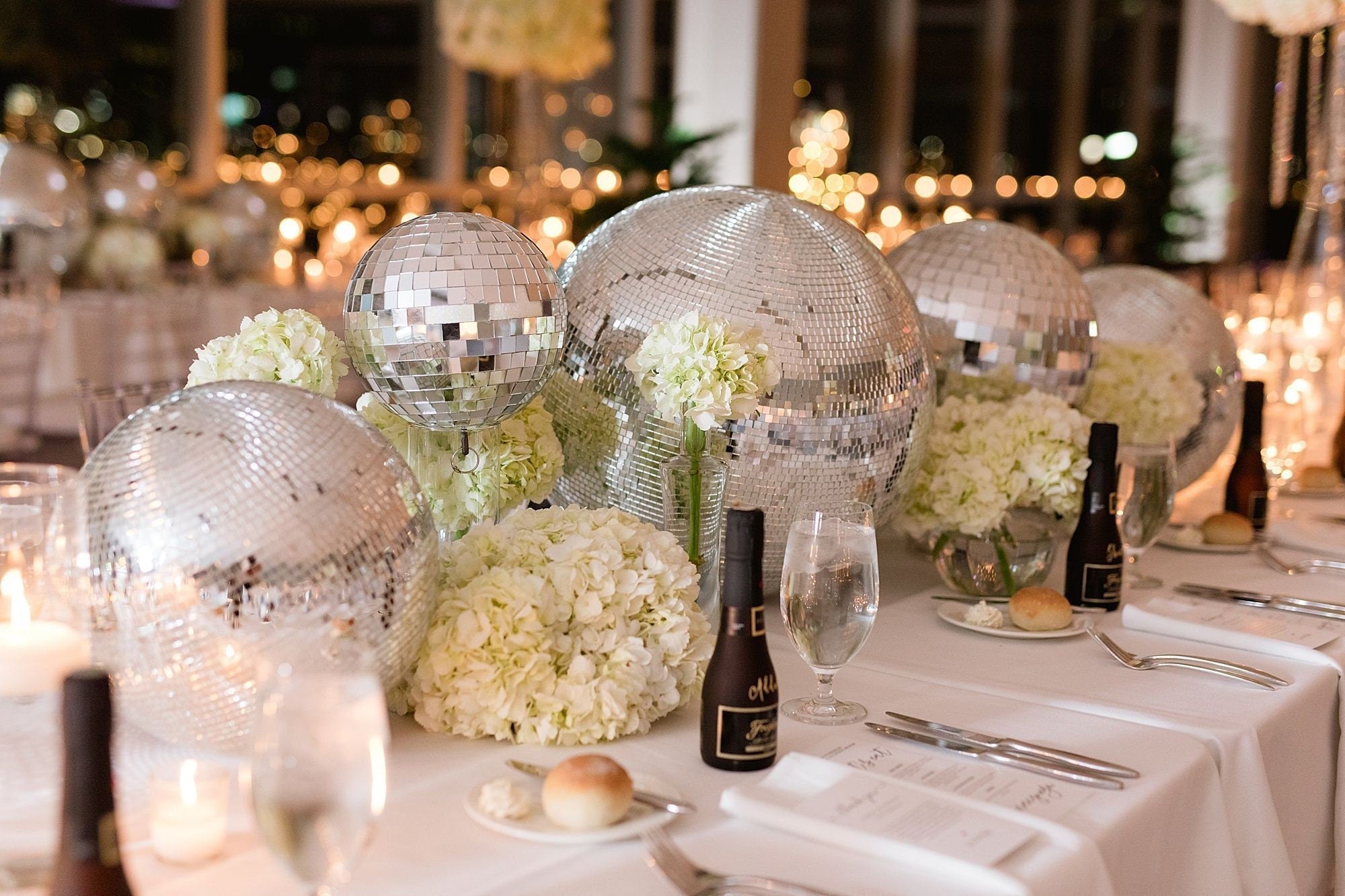 Silver disco balls used as wedding table centerpiece décor with candles