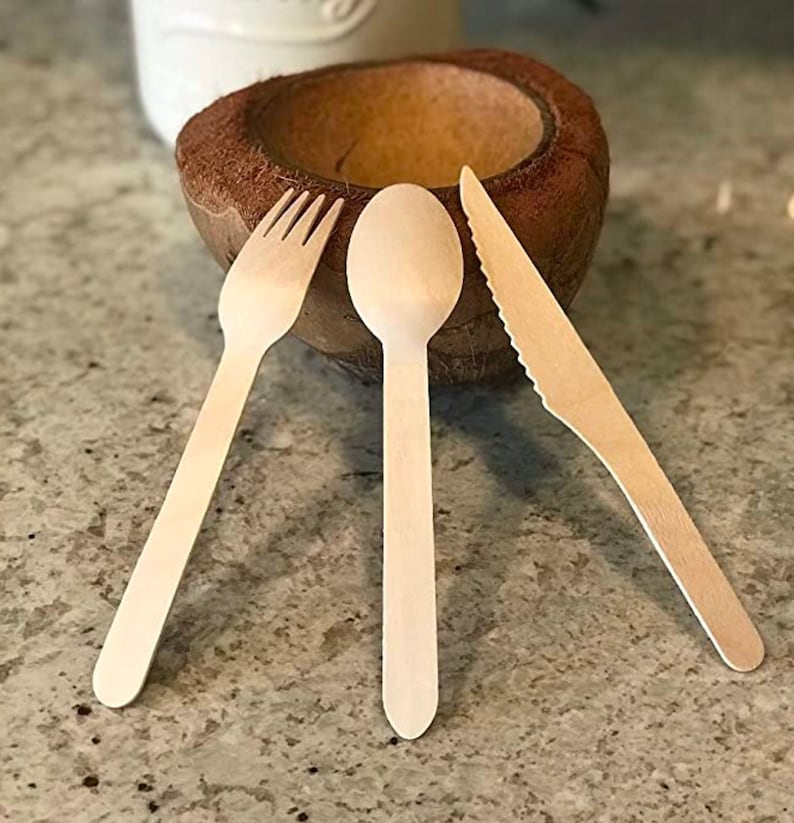 Disposable wooden cutlery set with 6-inch birch spoon, fork, and knife arranged on table for party dining.