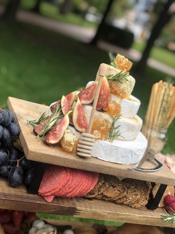 Honey dipper displayed on grazing table with figs, cheese, and bread