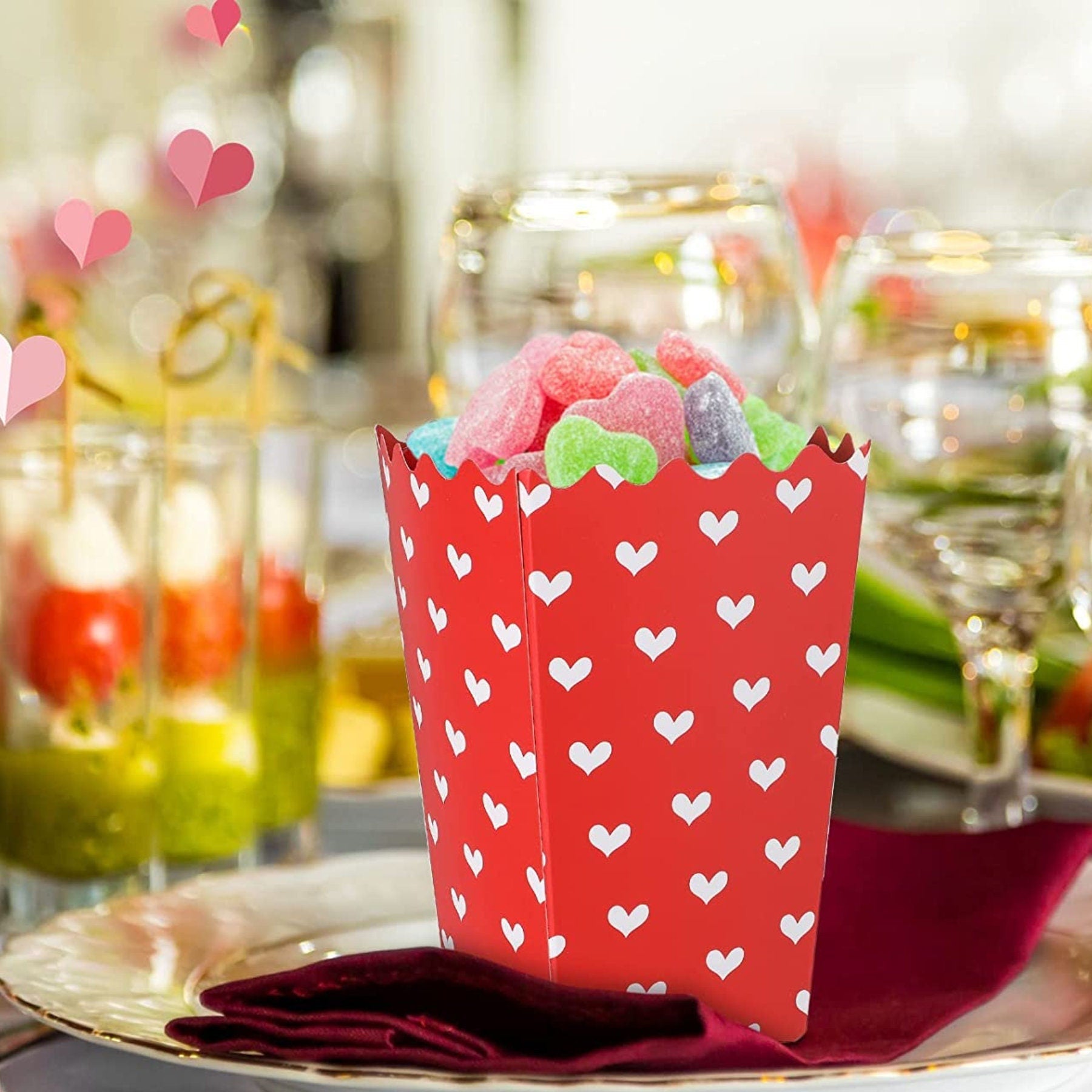 Heart print popcorn cup filled with colorful candy at elegant event table setup for party favors and celebration treats.