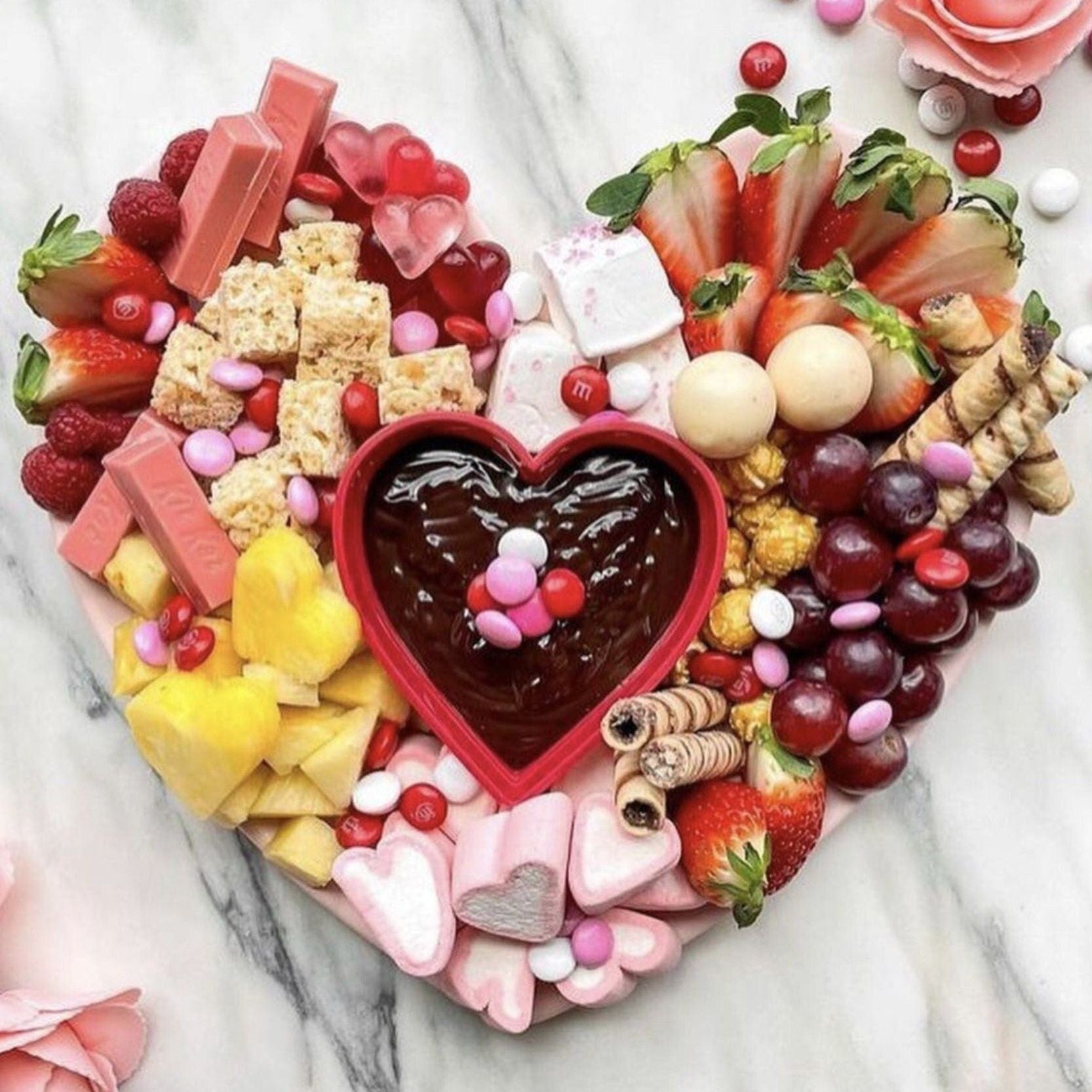 Romantic heart-shaped charcuterie board with chocolate dip, fruits, and desserts for Valentine’s Day