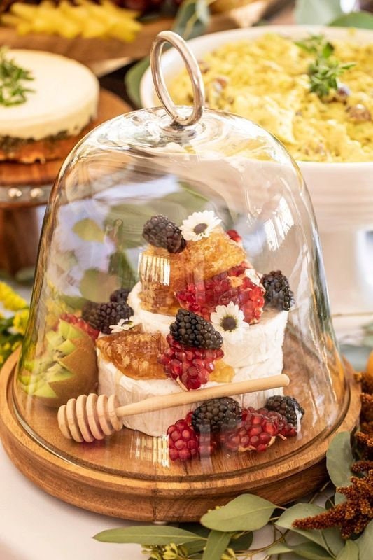 Wooden honey dipper displayed with fruit and dessert platter