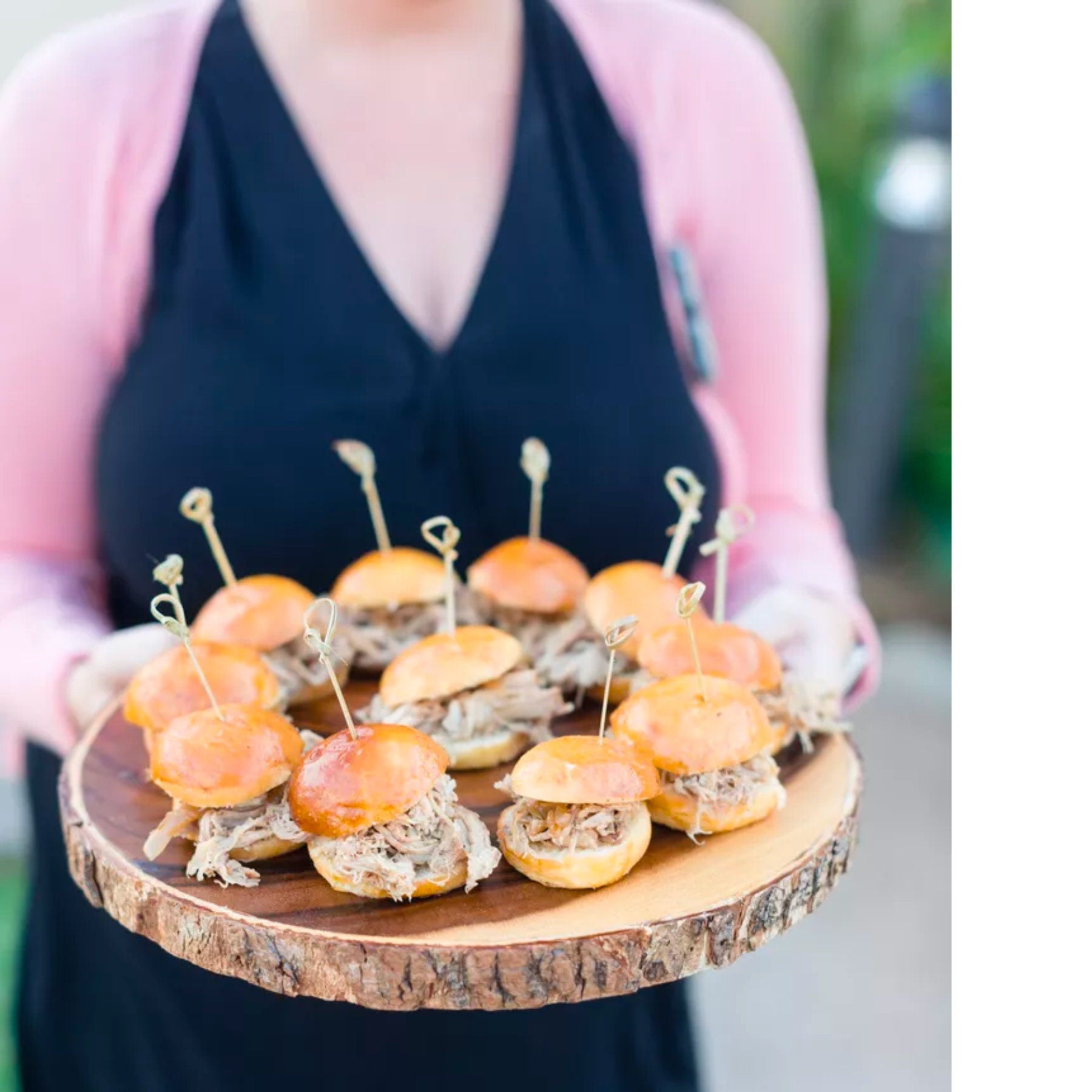 Assorted sliders served on a wooden platter using knotted bamboo charcuterie toothpicks