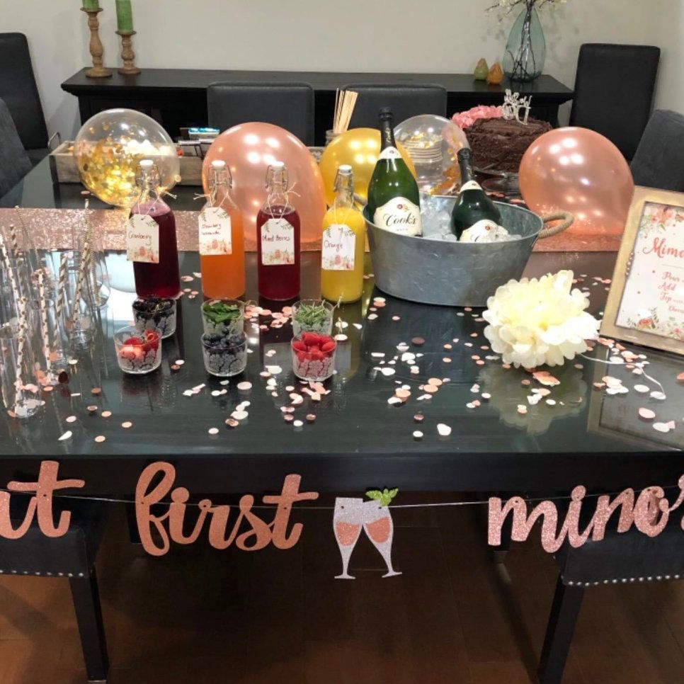 Styled brunch mimosa bar table with juice, fruit garnishes, and signage
