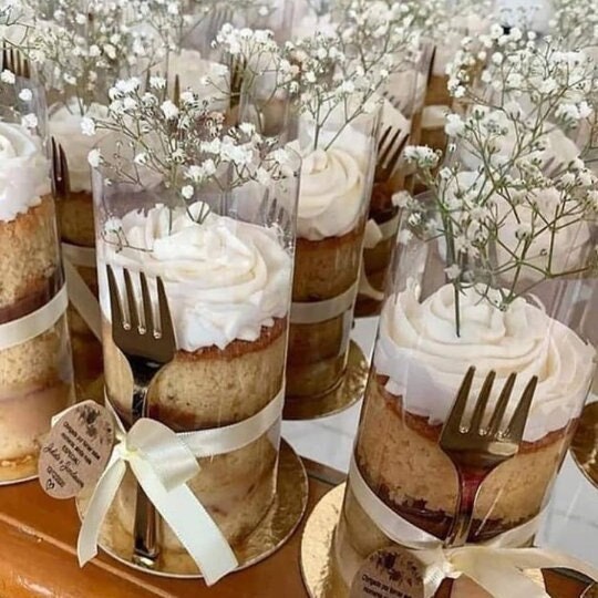 Close-up of a mini cake wrapped in a clear cake wrap on a gold board, showcasing elegant party favor details.