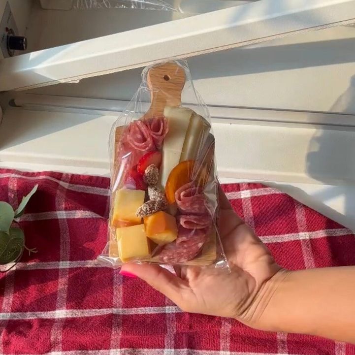 Individual board packaged in clear bag with meats and cheese for takeaway favor