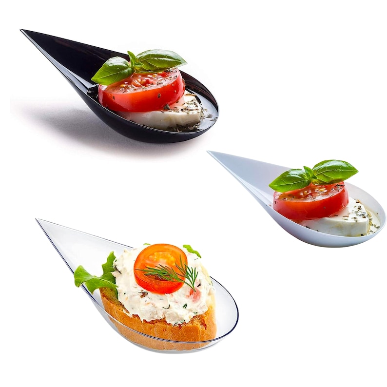 Mixed black and white tasting spoons with appetizers.