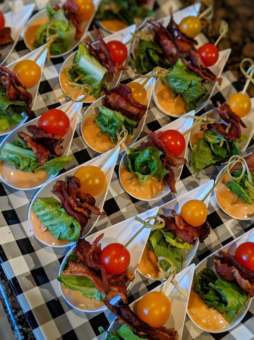 Party tray of white appetizer spoons with assorted bites.