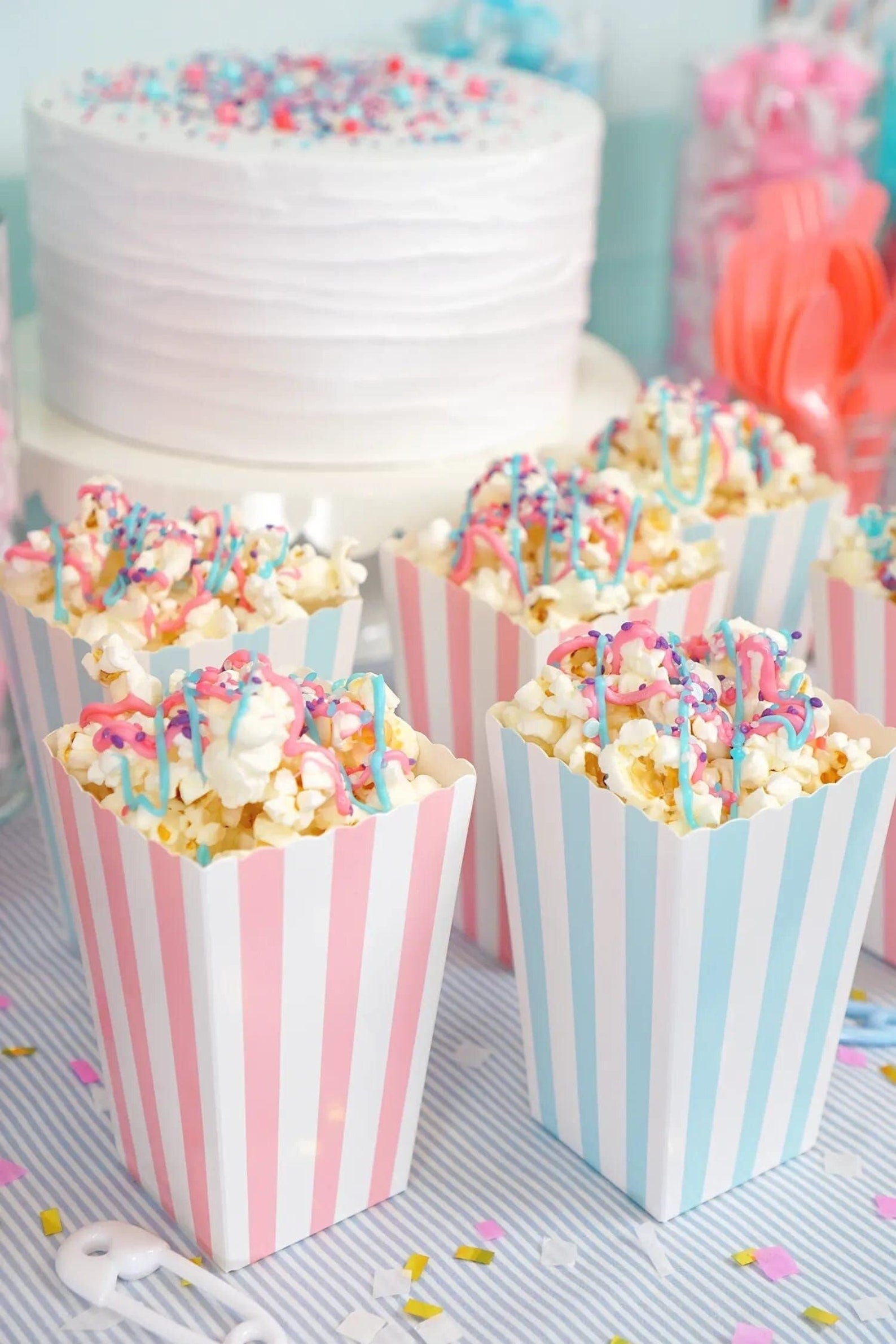 Striped popcorn cups holding mixed snacks for guests at an outdoor movie party.