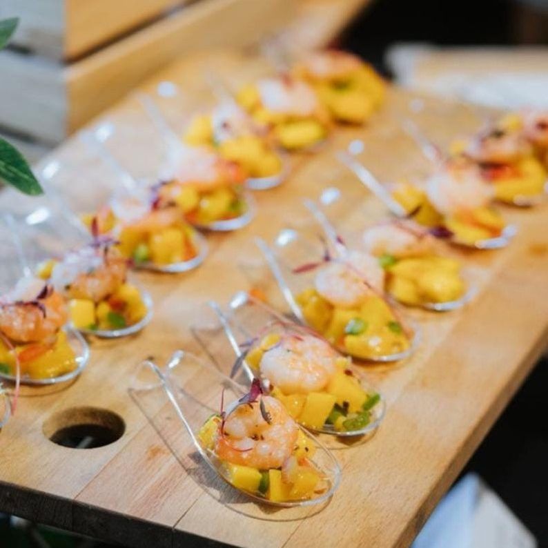 Premium tasting spoons showcasing elegant shrimp mango appetizer bites on rustic wooden serving board