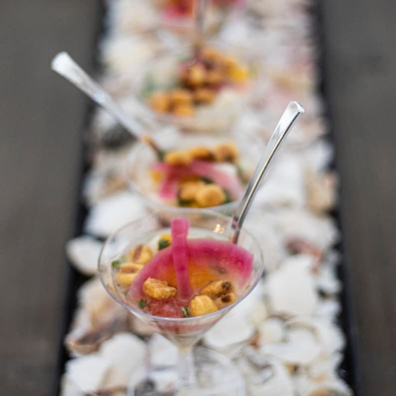 A mix of shrimp cocktail glasses and mini wooden forks arranged for a buffet, highlighting their practicality and elegance.