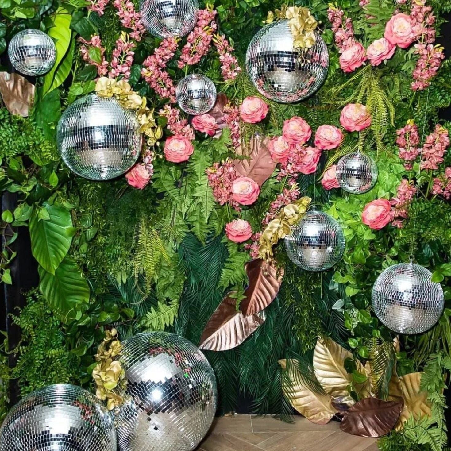 Silver disco balls of various sizes arranged for an eye-catching disco theme party backdrop.