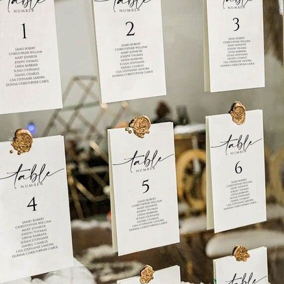 Hanging seating chart cards numbered 1–6 attached with gold adhesive wax seal stickers.