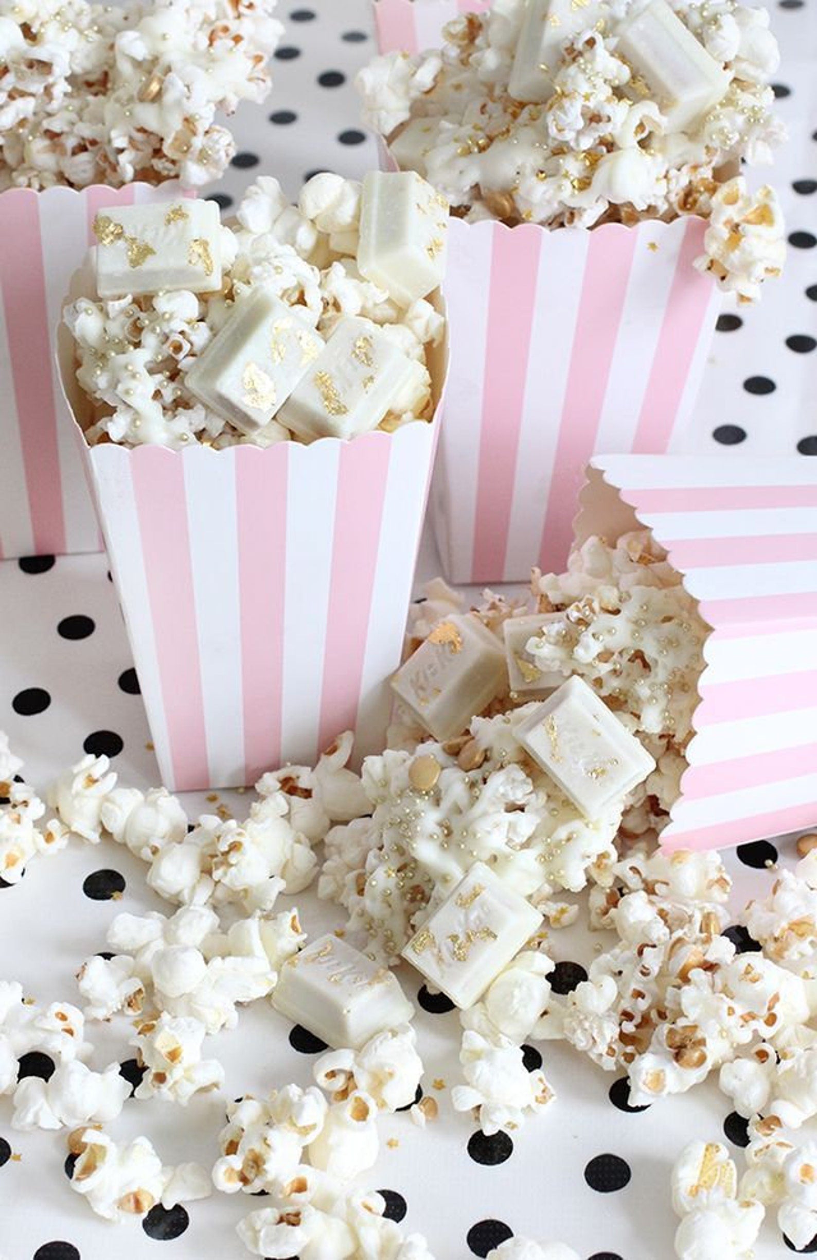 A set of 12 striped popcorn cups filled with candy used as popcorn party favors.