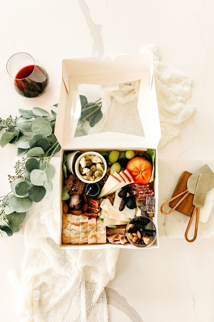 Charcuterie box favor with clear lid filled with fruit, cheese, and crackers for wedding or party grazing table