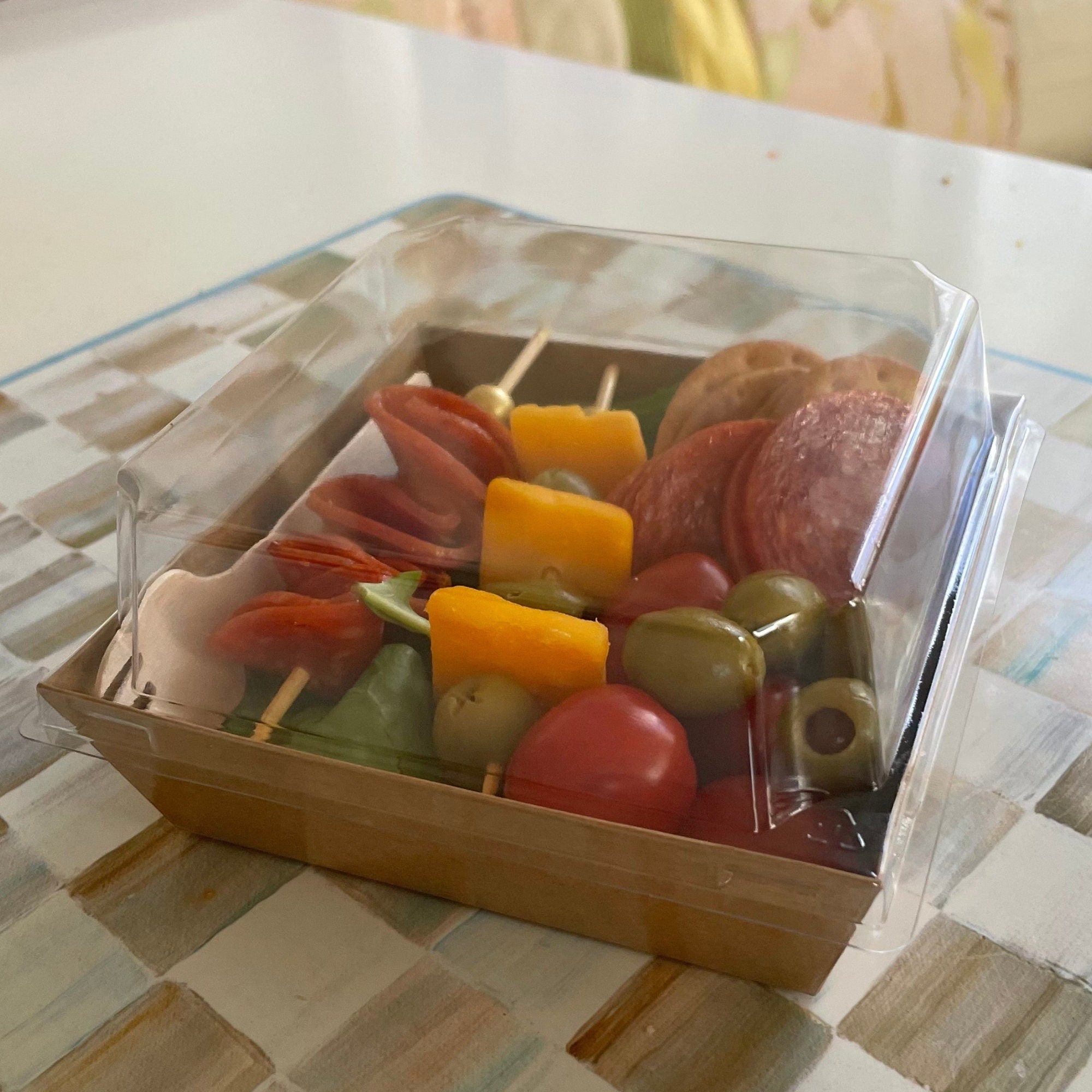 Four rustic square charcuterie favor boxes tied with twine filled with party snacks