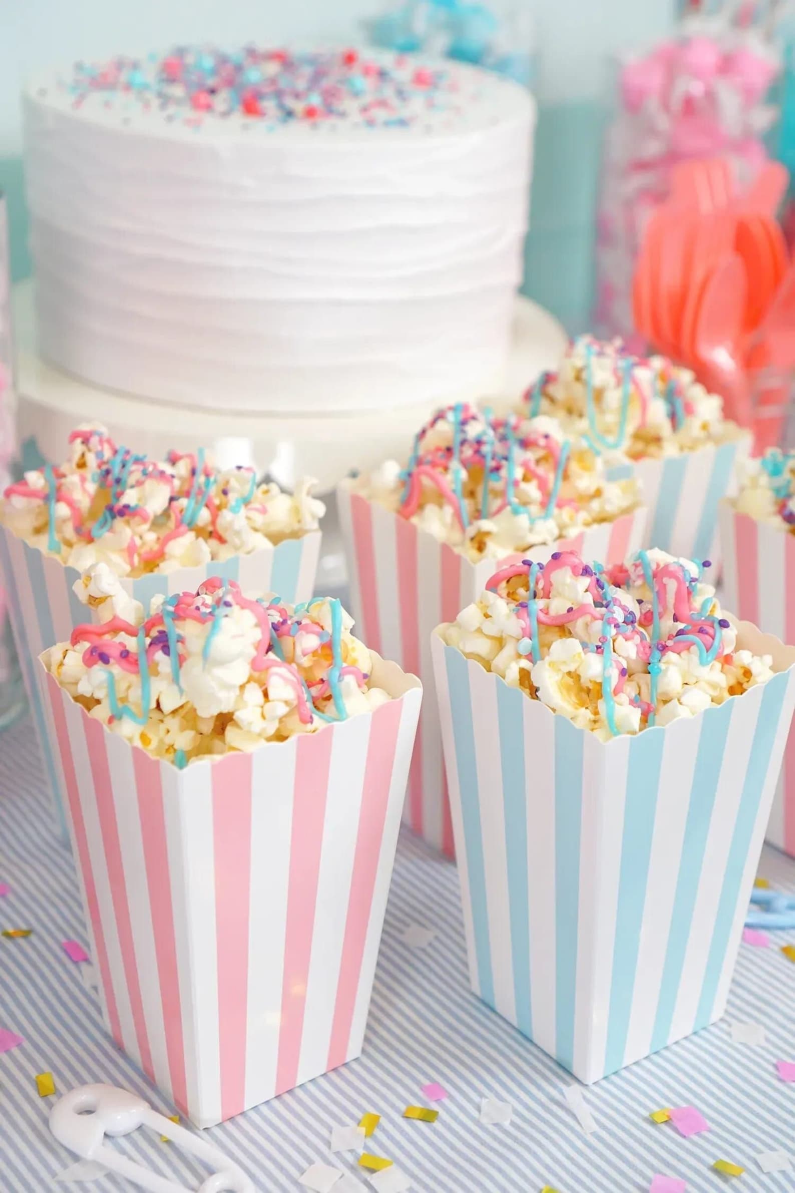 Striped popcorn cups filled with colorful popcorn displayed at a baby shower snack table.