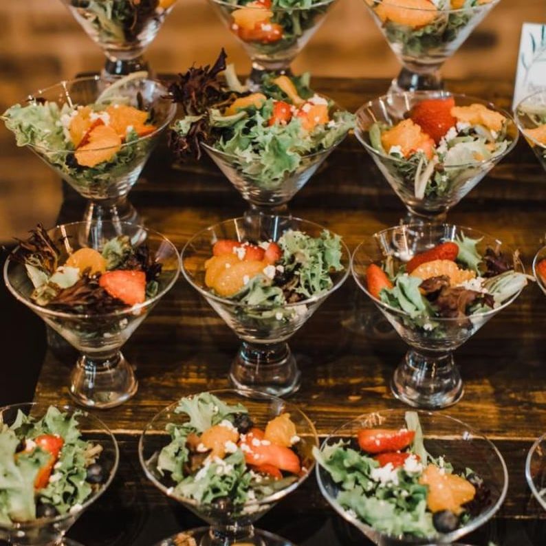 Clear 5oz individual salad cups for party with mini forks, filled with vibrant salads, displayed elegantly at a wedding buffet.