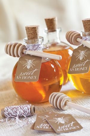 Small honey jars with wooden honey dippers used as wedding favors