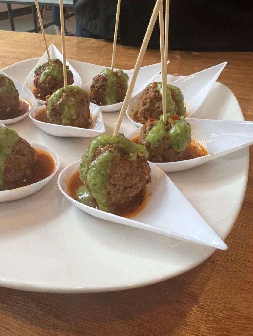 White appetizer spoons with meatball appetizers.