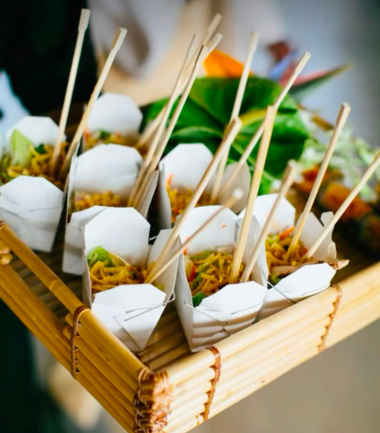 White Chinese take out boxes with wooden chopsticks filled with noodles for wedding catering.