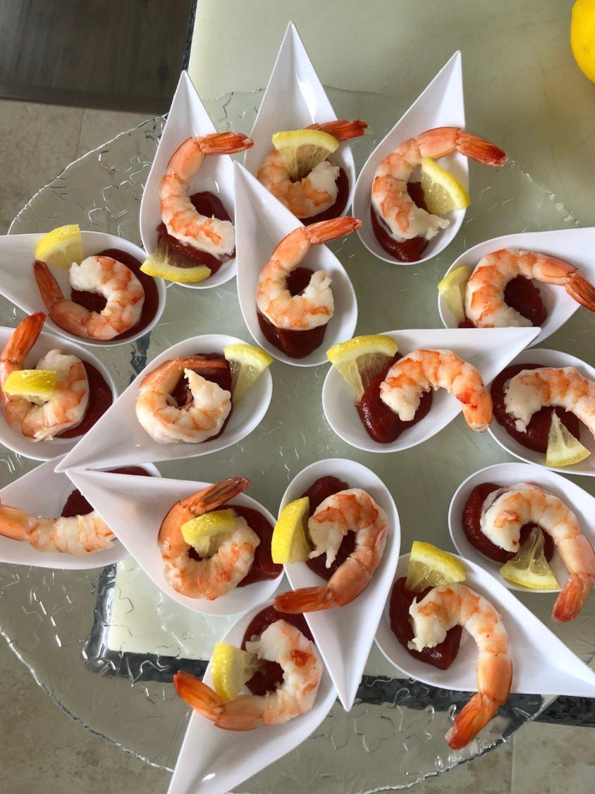 White tasting spoons with shrimp bites and garnish.