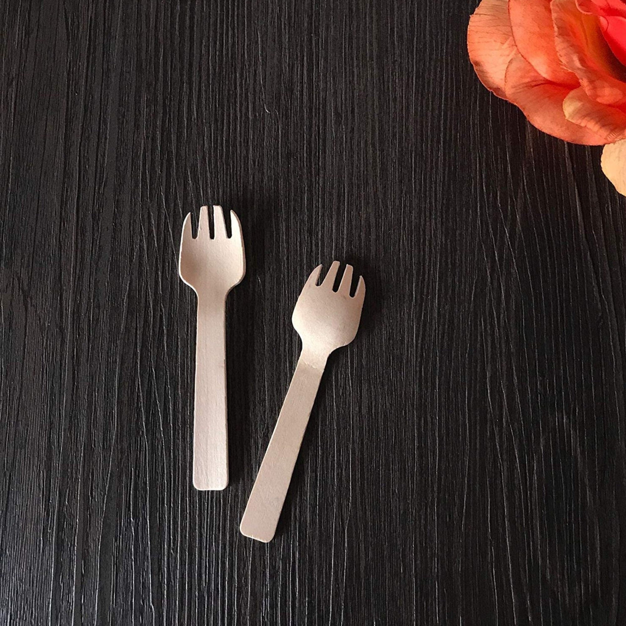 Mini wooden fork and spoon set on black background