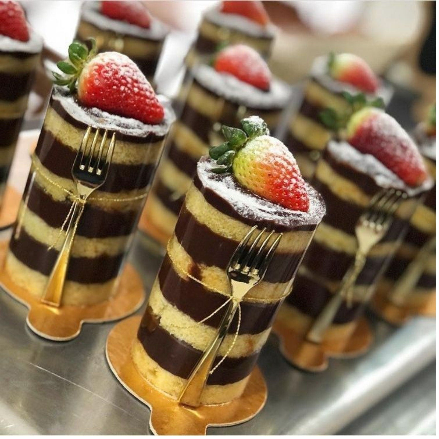 Gold mini fork resting beside a wrapped cake on a dessert table, highlighting stylish and practical presentation.