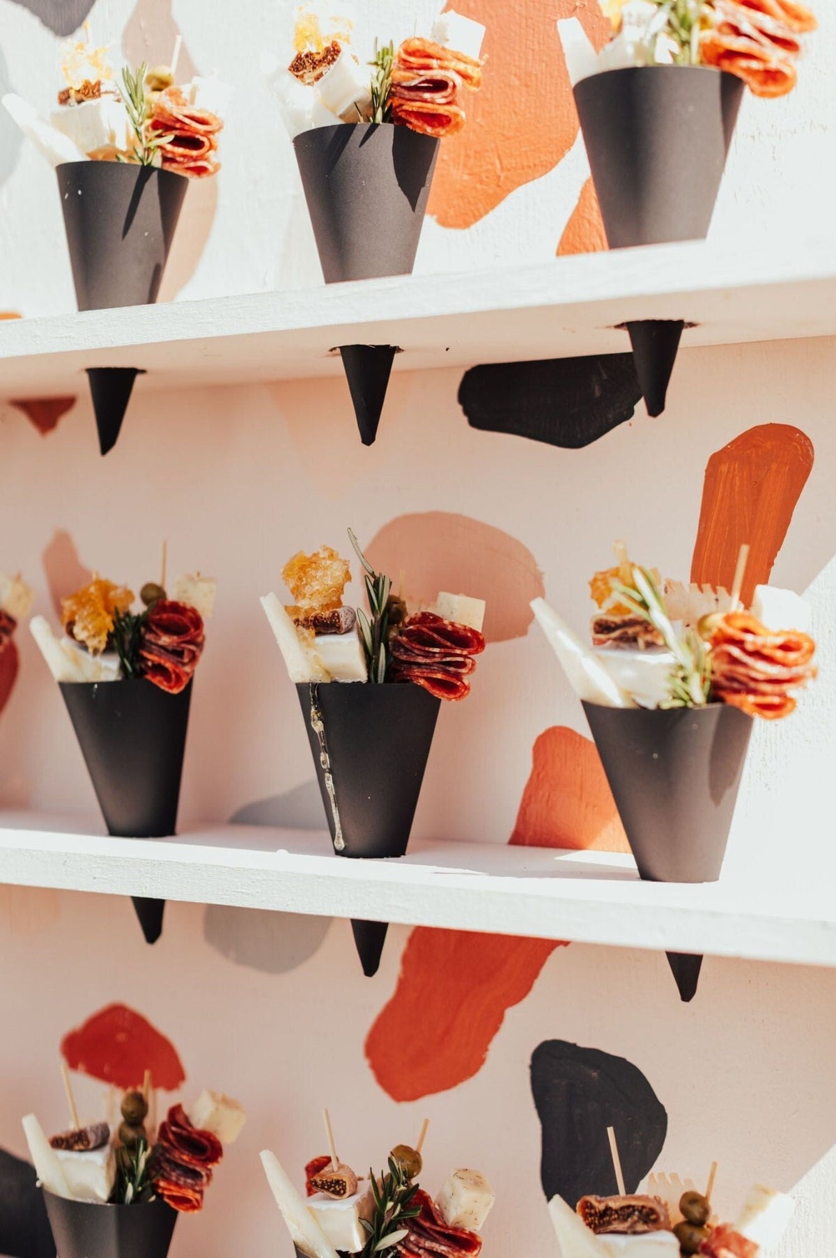 Disposable wooden charcuterie cups with various cheeses, meats, and crackers. Eco-friendly appetizer cones.