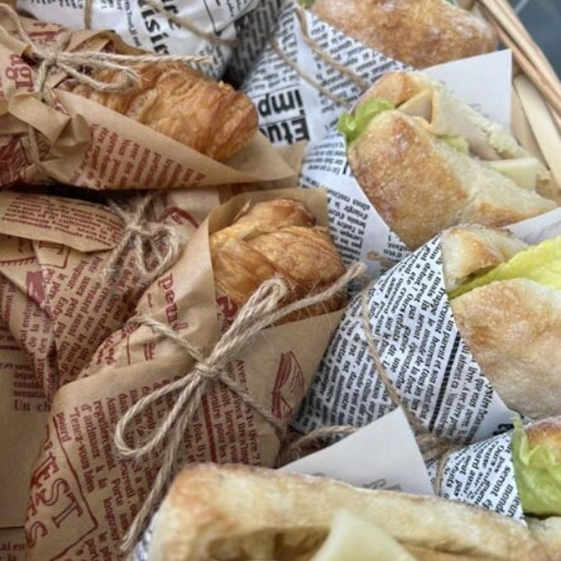 Croissants wrapped in vintage newspaper deli paper sheets tied with rustic twine for stylish food presentation and serving.