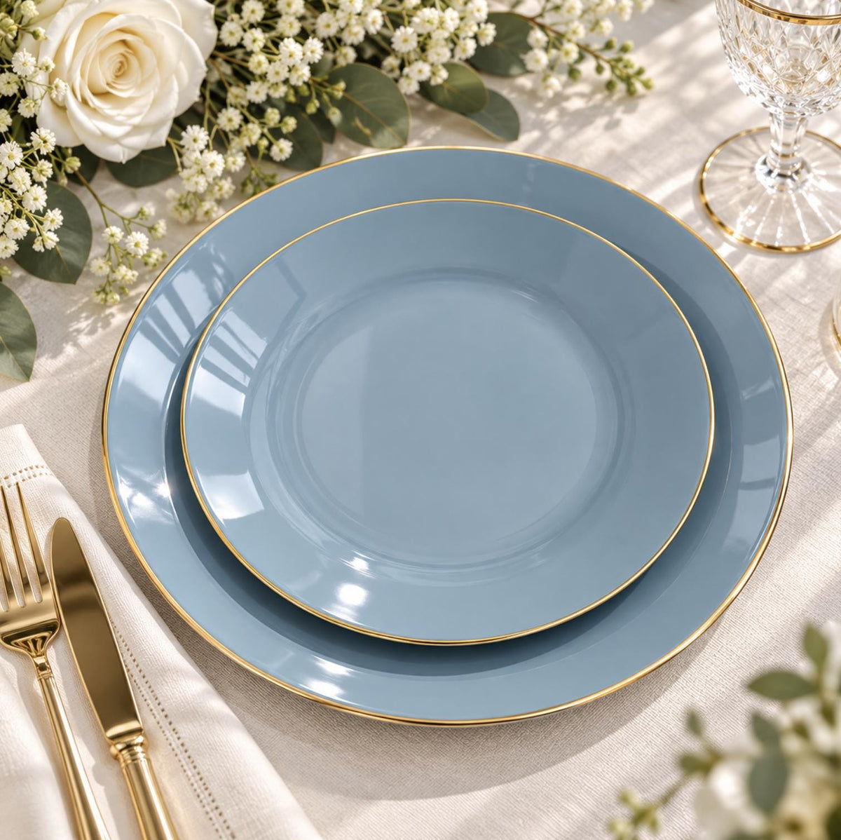 Clear baroque charger plate with ornate gold rim, set with dusty blue dinnerware. Elegant wedding decor.