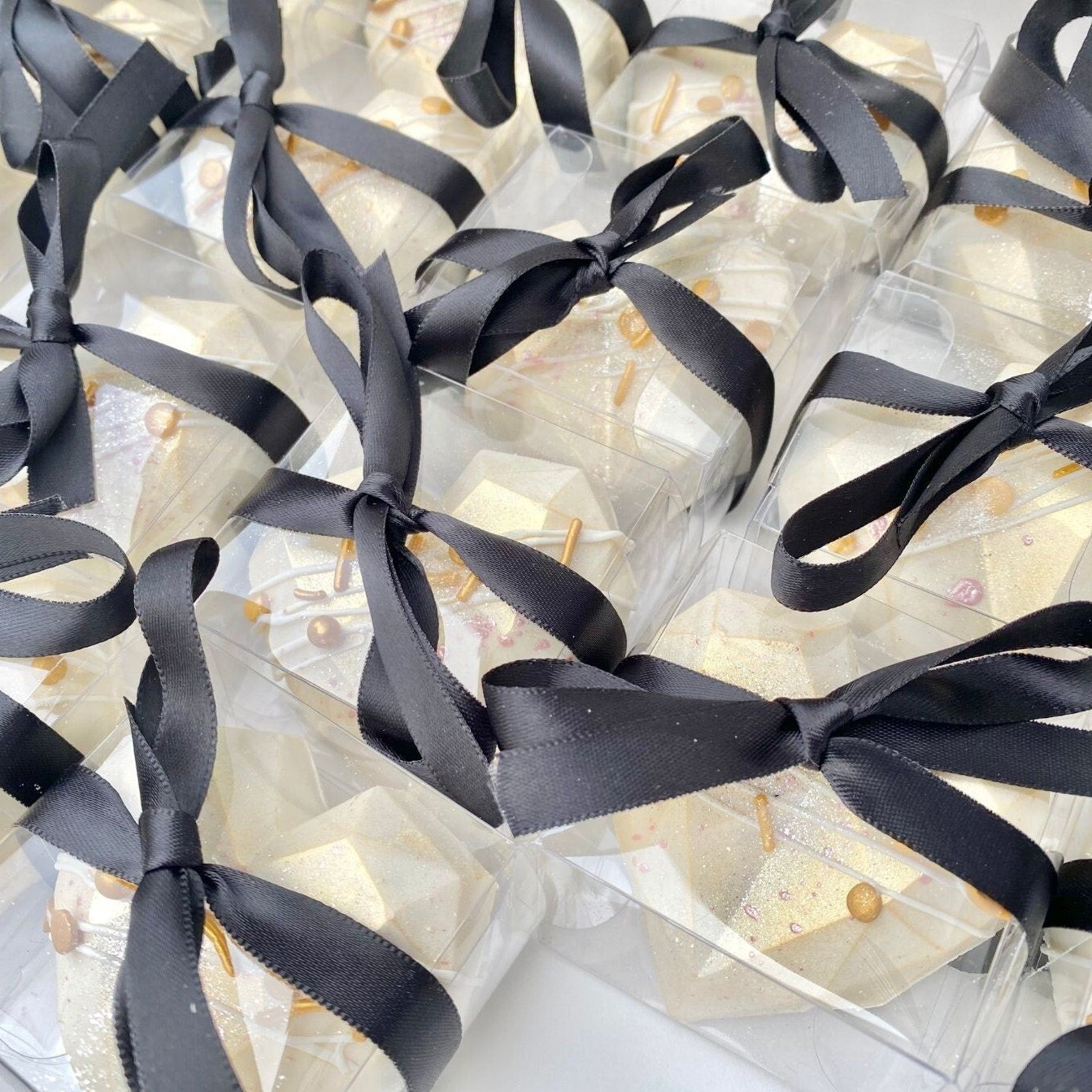 Dozens of ribbon-tied clear macaron/Oreo favor boxes ready for an event