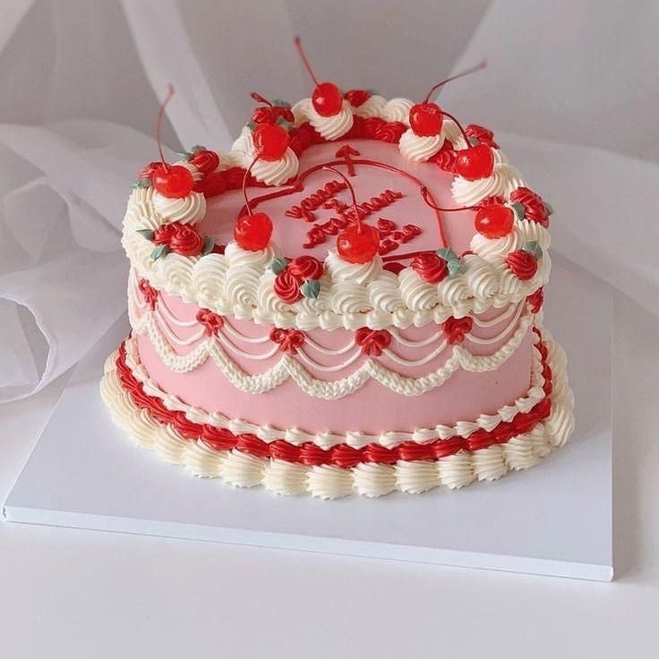 Heart-shaped celebration cake with realistic artificial fruit and beaded rim frosting detail – dessert table centerpiece.
