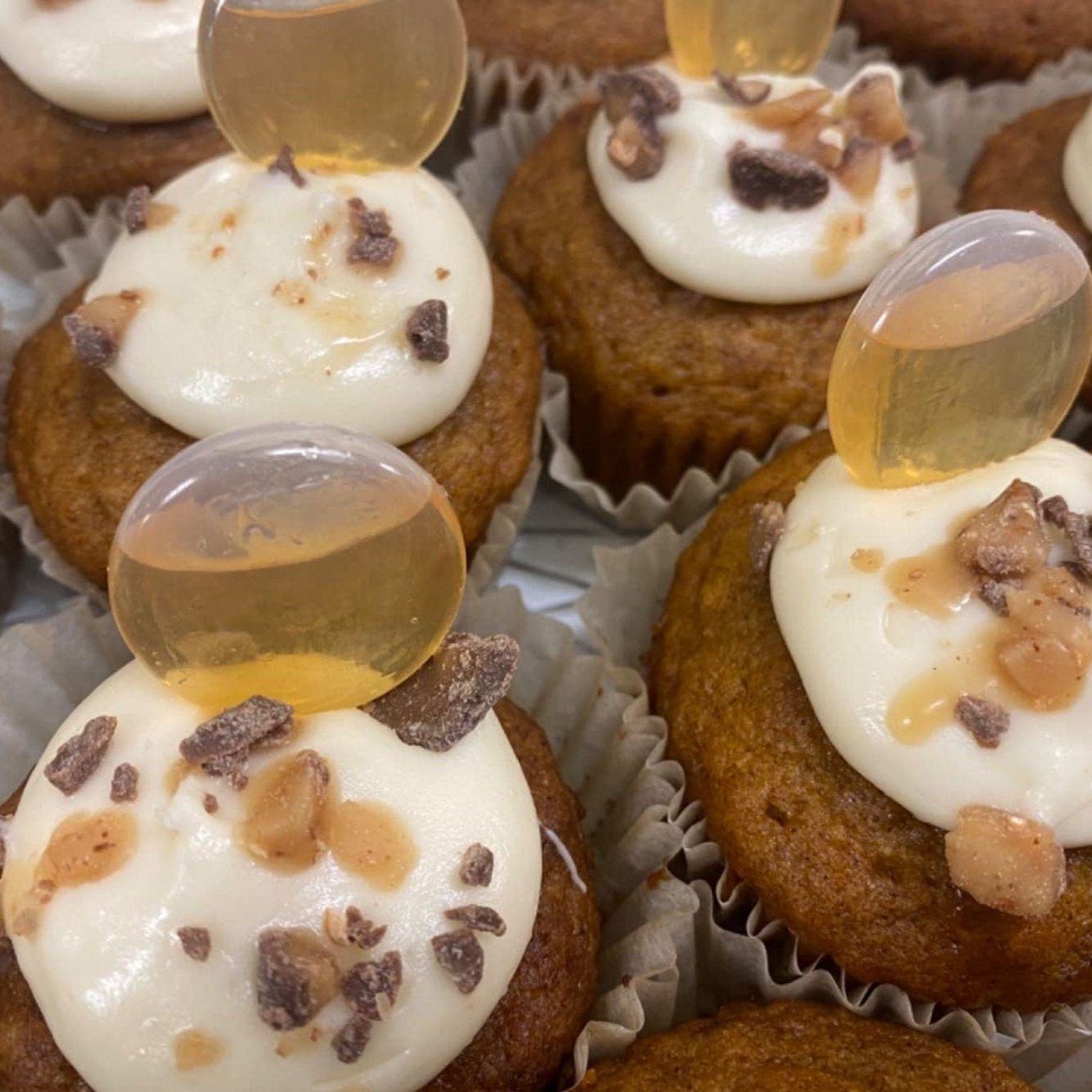 Cupcakes with white frosting, chocolate chips, and a clear mini pipette inserted.