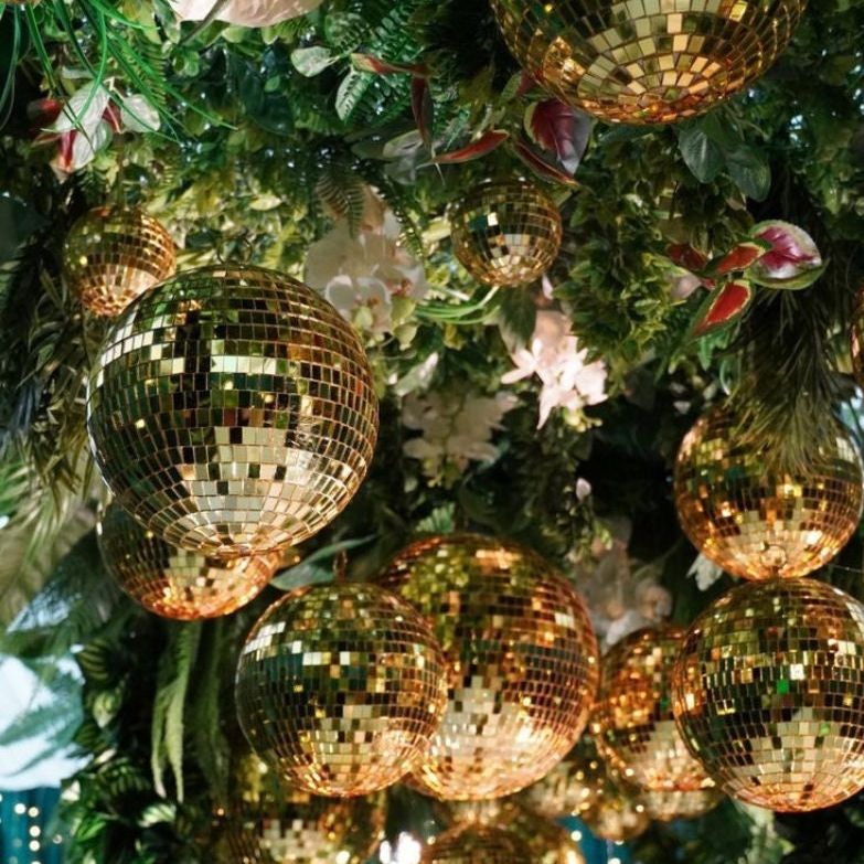 25 shimmering gold disco balls of assorted sizes, adding sparkle as trendy mirror balls for birthdays or themed gatherings.