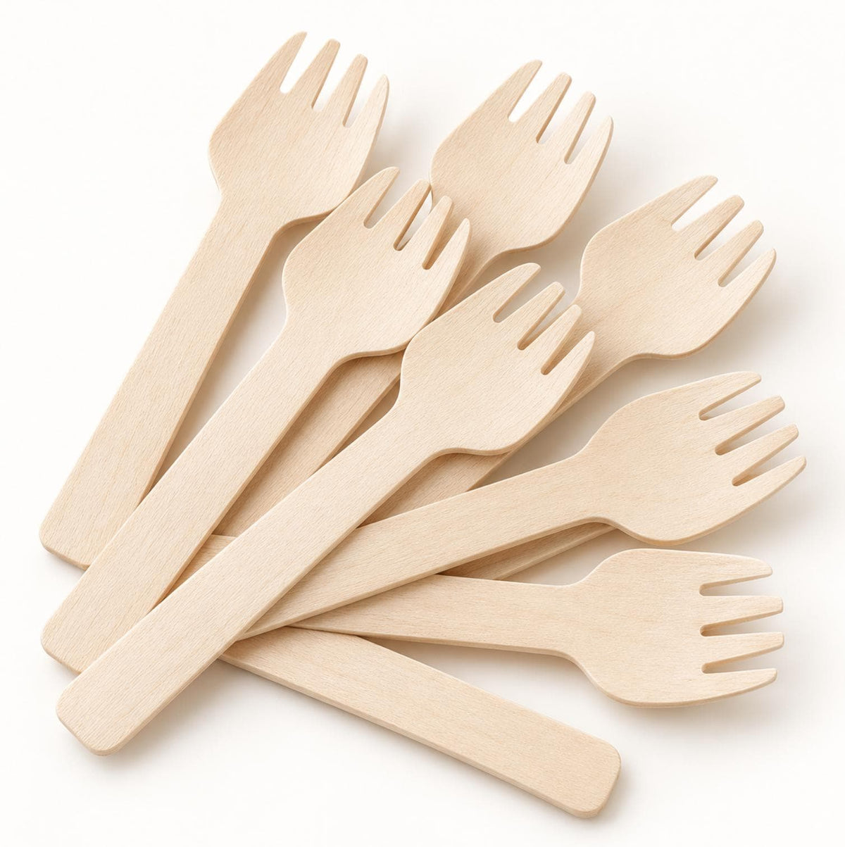 Disposable wooden cutlery set (fork, spoon, knife) on a table with grilled meat and BBQ items for a party.