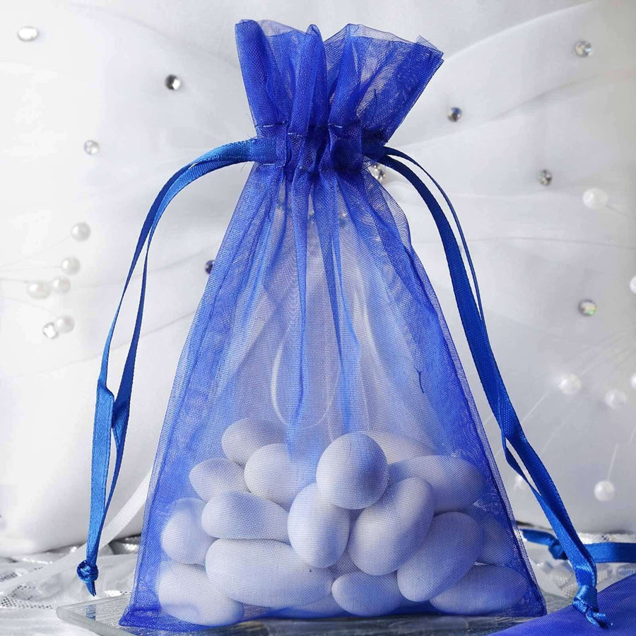 Royal blue organza drawstring gift bag filled with pastel-colored candies – elegant 4"x6" favor pouch for weddings and special events