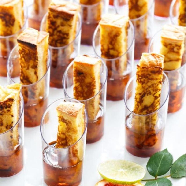 Clear acrylic cups with mini forks serving grilled cheese and tomato soup at an event