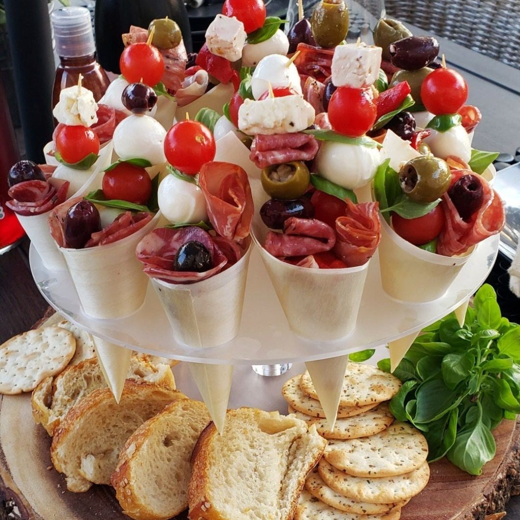 Acrylic charcuterie cone stand filled with bamboo cones of meats, cheese, and vegetables